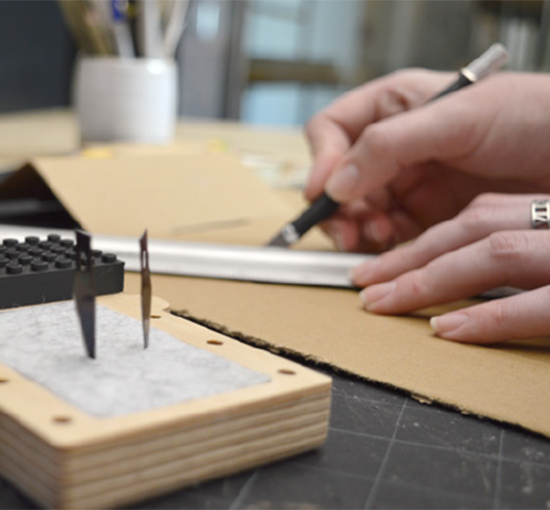 hands cutting cardboard with exacto knife