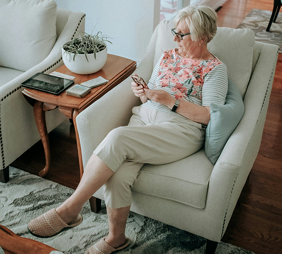 elderly woman sitting next to plant