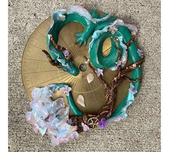 Clay sculpture of a green Chinese dragon laying in a circle on top of a metal plate