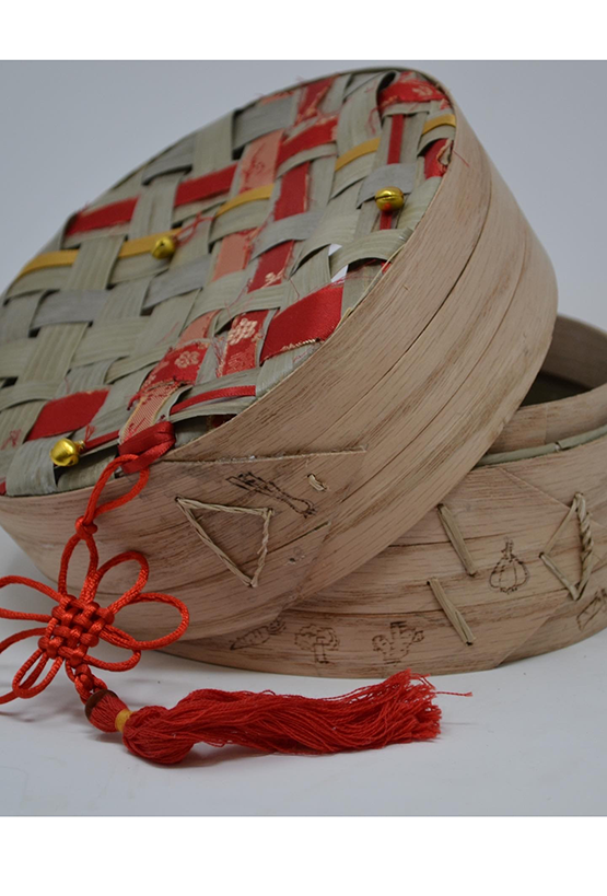 Wooden woven steamer basket with red ribbon and drawings of vegetables on the side