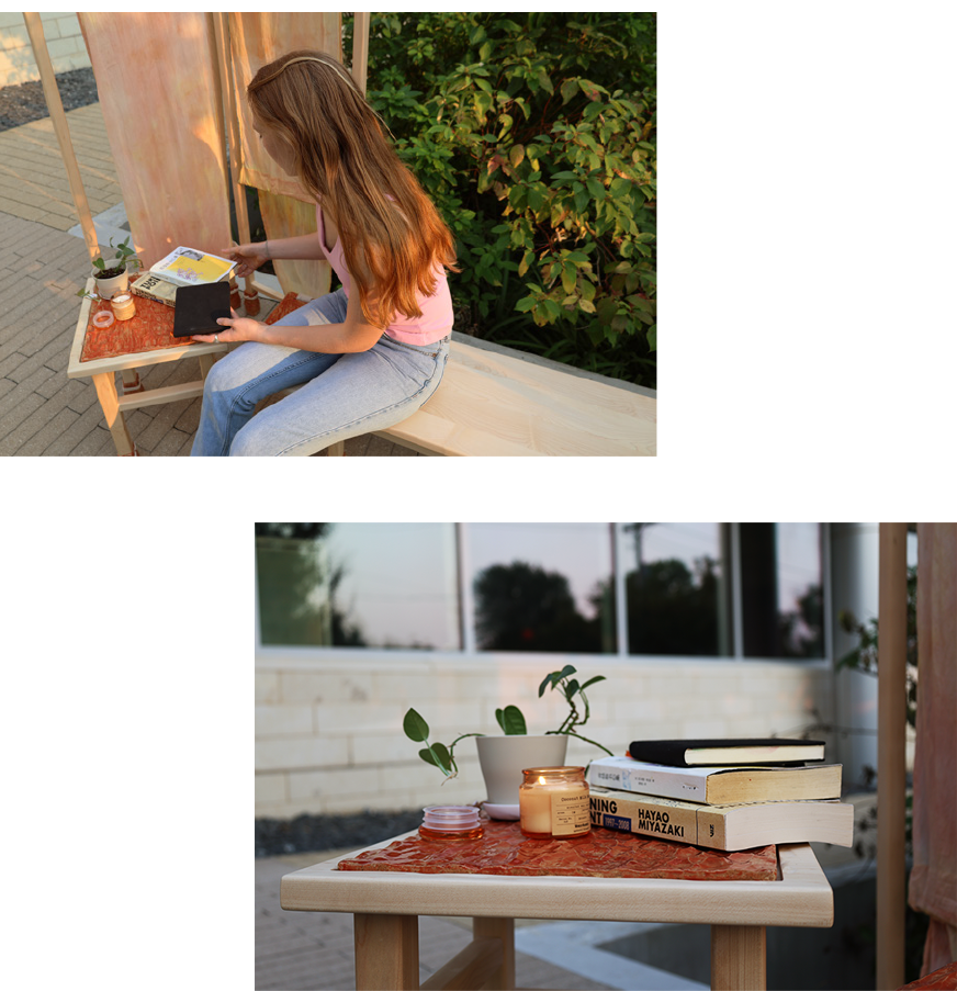 Project partner sitting on bench and books, a candle, and a plant on the table