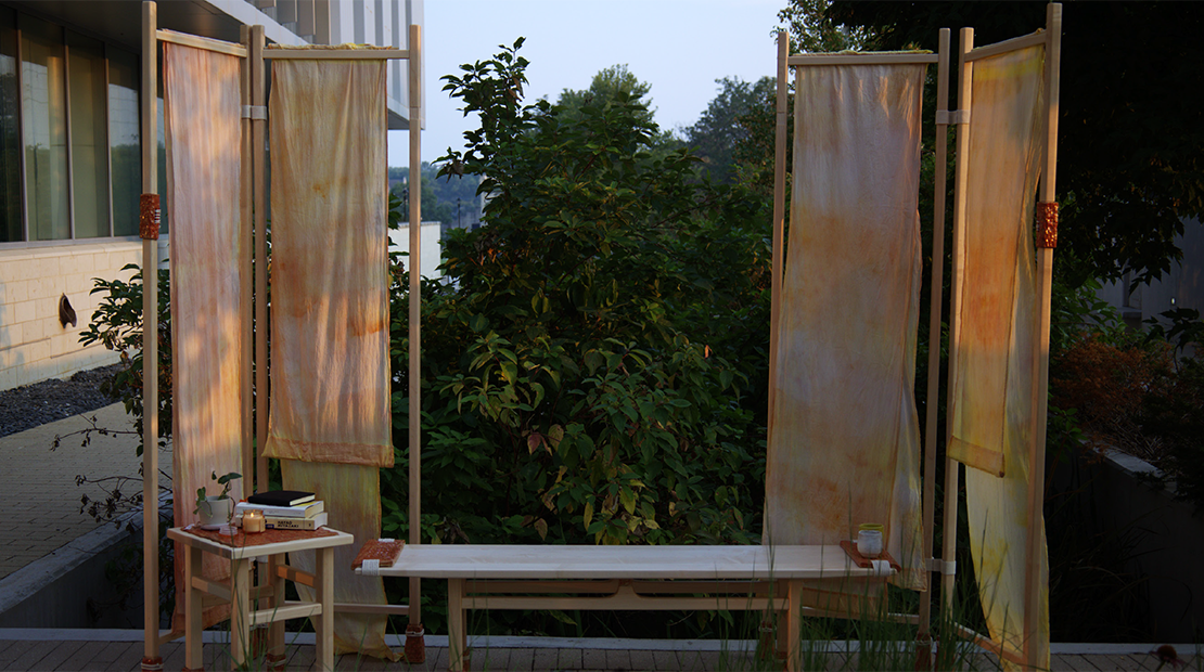 The Sunware Set furniture set (a bench, a small table, and four sunshades) on display in front of some trees